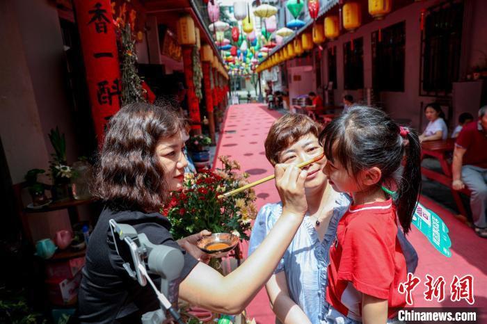 长辈为小朋友点雄黄以驱避毒虫。　张畅 摄