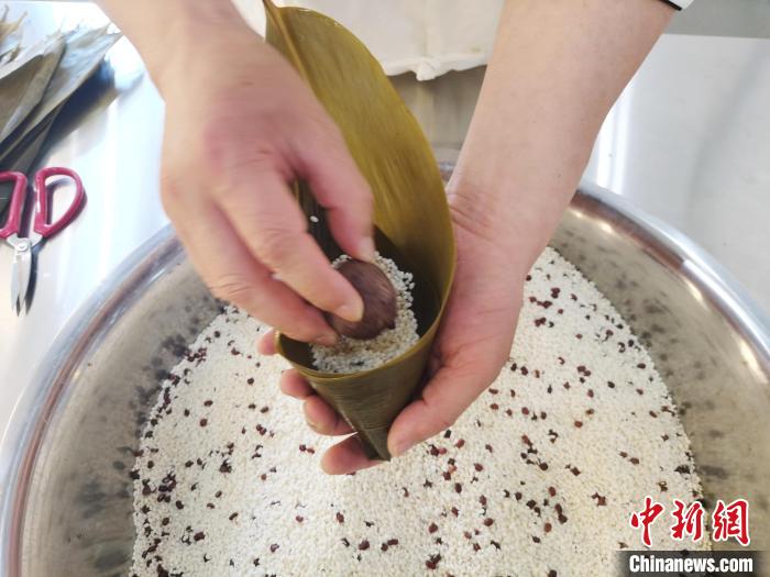 胡建民将豆沙馅填入粽子中 张雨滴 摄