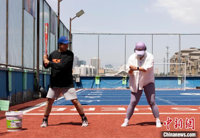 林智薰(左)指导学员练习棒球。　杨迪 摄