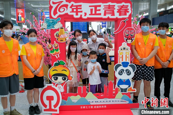 图为重庆北站候车大厅，旅客与铁路青年志愿者们在成渝铁路开通运营70周年的纪念展板前合影留念。 <a target='_blank' href='/'>中新社</a>记者 何蓬磊 摄