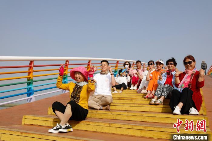 台青(左二)在沙湖景区七彩鹊桥上与市民合照。　杨迪 摄